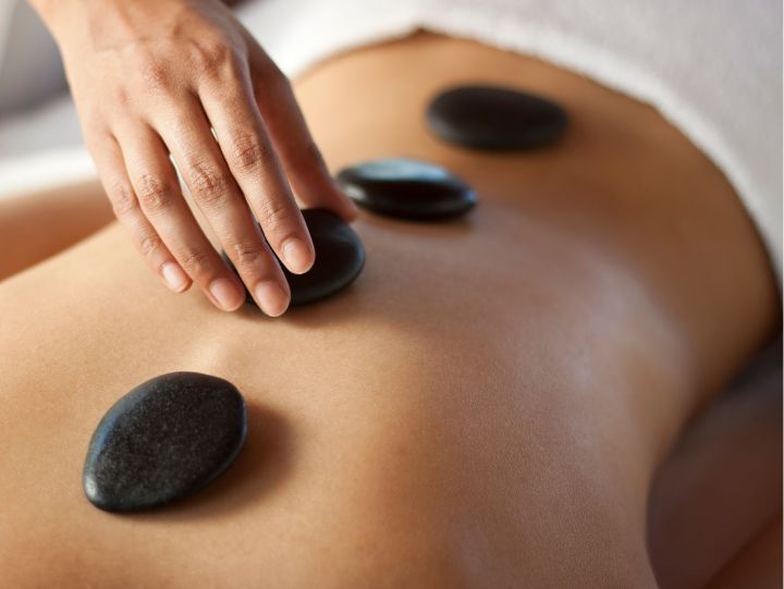 A hand putting hot stones on someone's back.