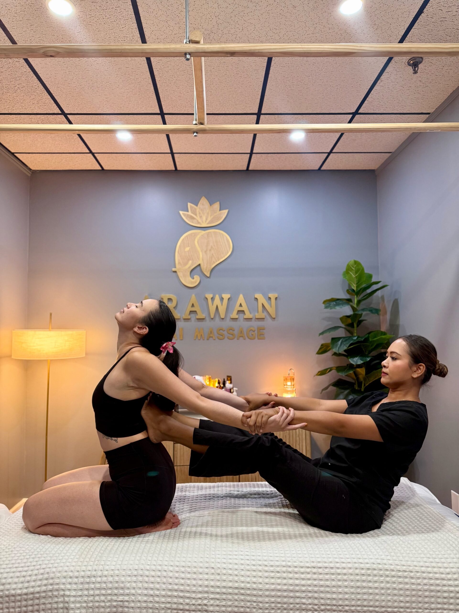 A female masseuse pushing a woman on the back with foot.