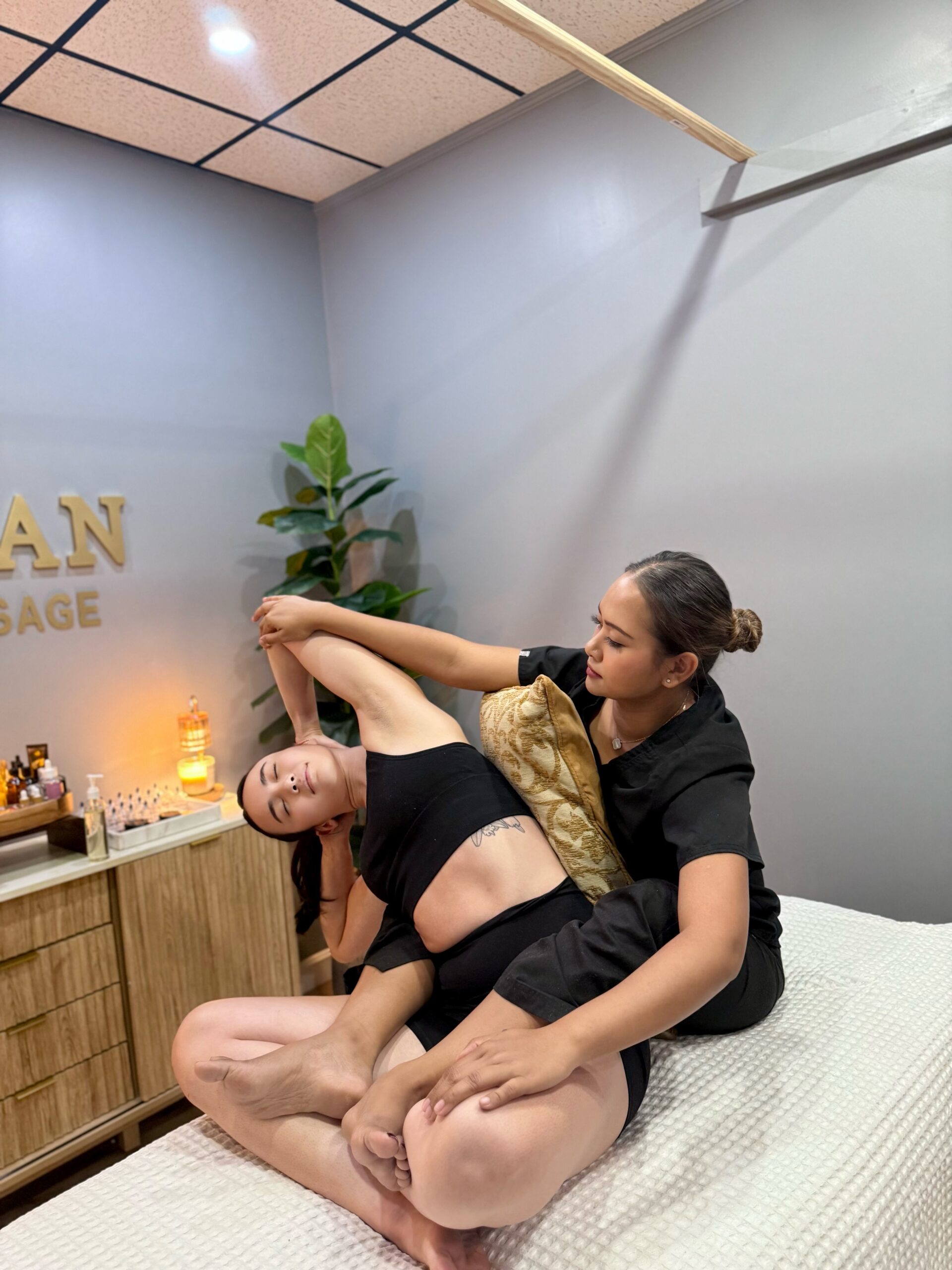 A female masseuse stretching a woman's side body.