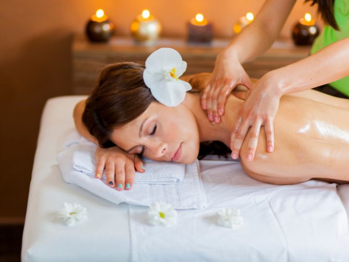 A female with a white flower on her ear getting massage.
